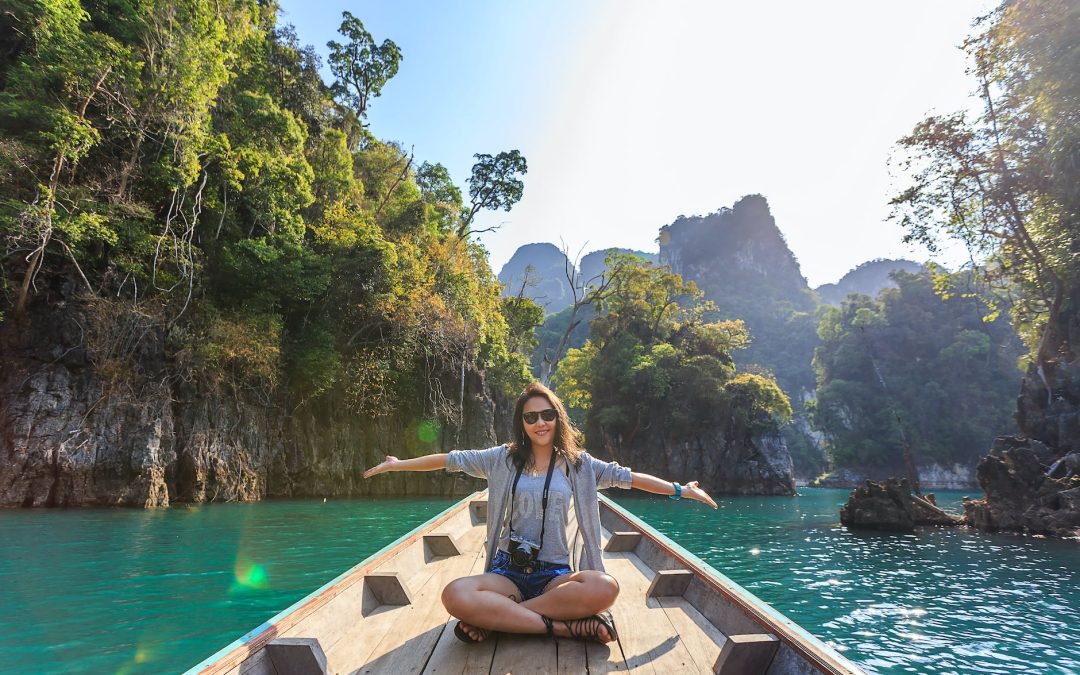 photo of woman sitting on boat spreading her arms